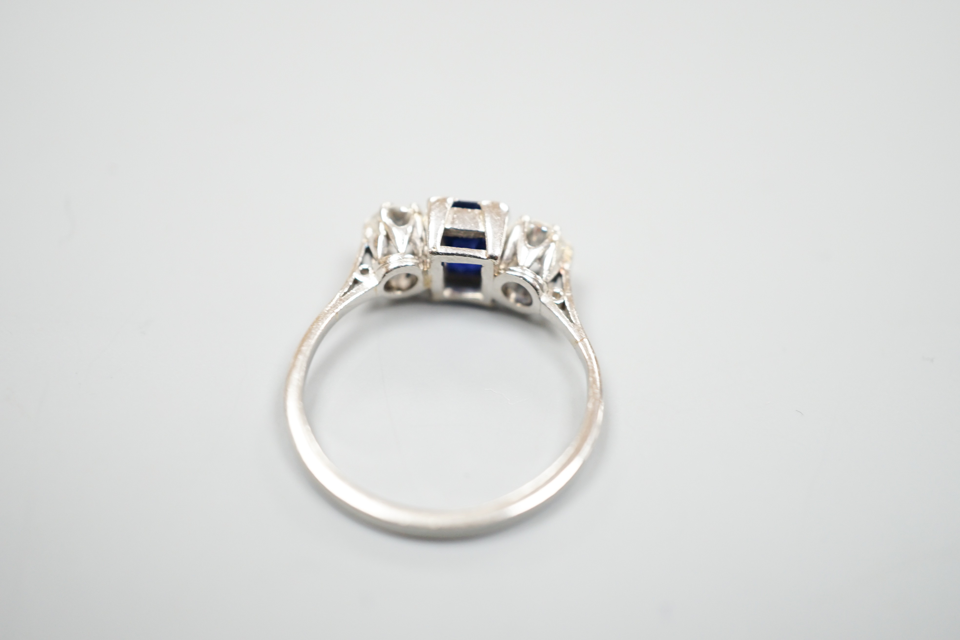 A white metal (stamped plat), sapphire and diamond set three stone ring, size K, gross weight 3.6 grams.